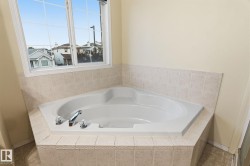 Corner soaking tub with tiled surround and window above - 