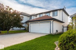 Two-story residence featuring white siding, a two-car garage, and a concrete driveway - 