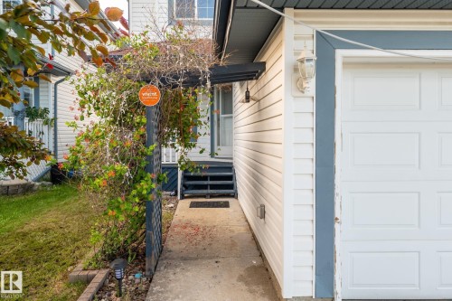 White siding exterior with a paneled garage door and a decorative wall lantern - 1906 37B Av, Edmonton, AB 