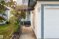 White siding exterior with a paneled garage door and a decorative wall lantern - 