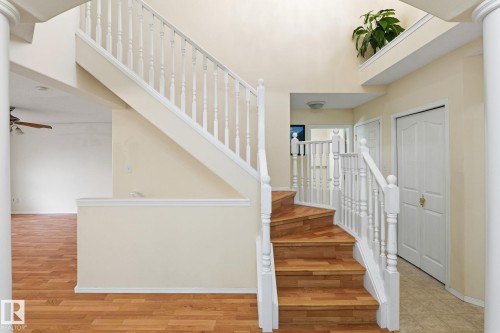 Grand central staircase featuring wood-finish treads and white balusters - 1906 37B Av, Edmonton, AB 