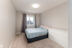 Neutral-toned bedroom featuring a light-colored carpet, a double-paned window, and a ceiling-mounted light fixture - 
