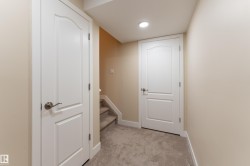 Carpeted hallway featuring a recessed ceiling light, two paneled doors with brushed nickel hardware, and neutral wall paint - 