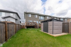 Backyard featuring a modern storage shed with wood-finish paneling and dark trim, positioned on a gravel base - 