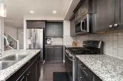 Kitchen featuring dark wood-finish cabinetry and stainless steel appliances - 