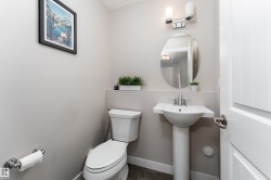 Powder room featuring a pedestal sink, oval vanity mirror, and chrome wall sconce lighting - 