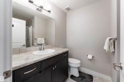 Bathroom featuring a dark wood-finish vanity with a light-colored countertop and an oval undermount sink, complemented by a chrome-finish faucet - 