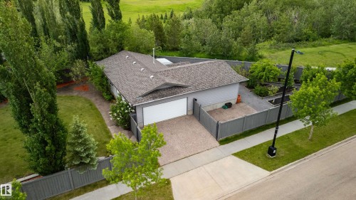 Single-story residence featuring a two-car garage with an overhead door, a shingled roof, and gray siding - 704 Wildwood Point(E), Edmonton, AB 