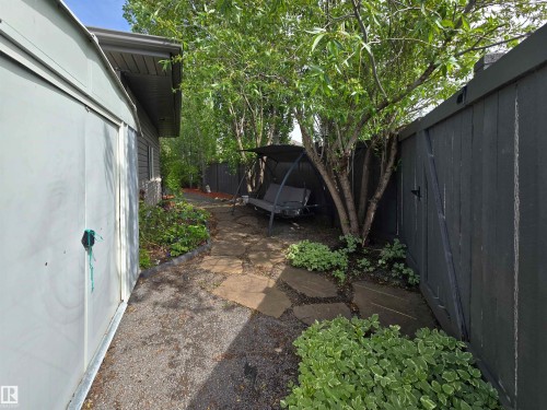 Private outdoor space featuring a paved pathway, established trees, and varied groundcover plantings - 704 Wildwood Point(E), Edmonton, AB 
