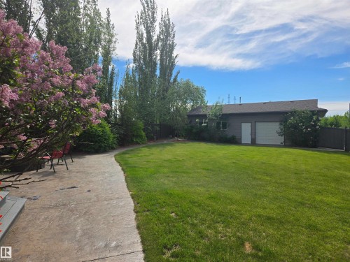 Expansive green lawn with a curved concrete pathway and mature trees - 704 Wildwood Point(E), Edmonton, AB 