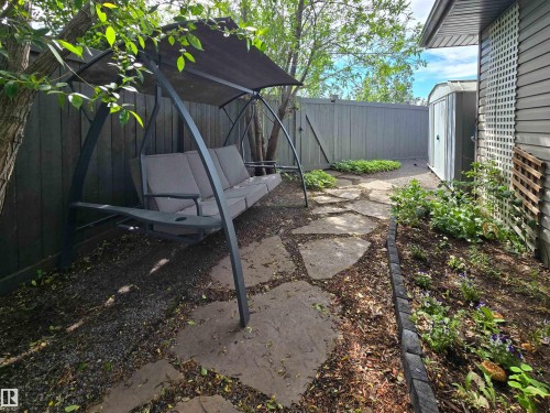 Landscaped side yard featuring a flagstone pathway, garden beds with established plantings, and a privacy fence - 704 Wildwood Point(E), Edmonton, AB 