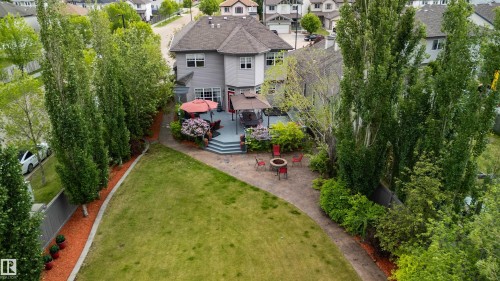 Expansive backyard featuring a large green lawn, multi-level composite deck, and a paver patio with a fire pit area - 704 Wildwood Point(E), Edmonton, AB 