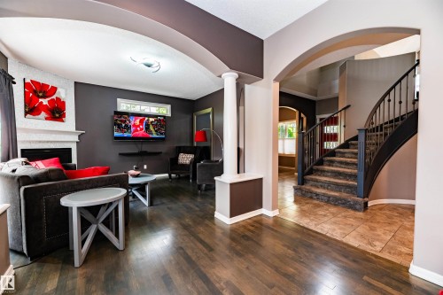 Open living space featuring dark wood-finish flooring, a white mantel fireplace, and a window transom - 704 Wildwood Point(E), Edmonton, AB 
