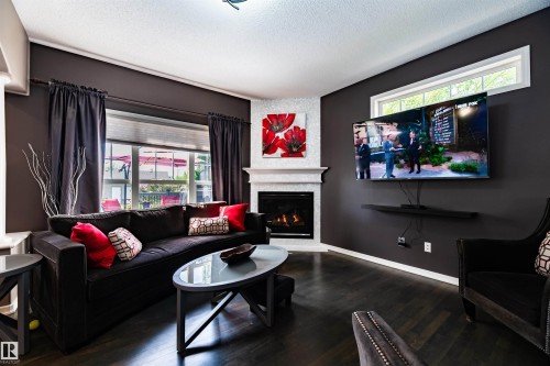 Living area featuring dark wood-finish flooring and a corner fireplace with a white mantel and mosaic tile surround - 704 Wildwood Point(E), Edmonton, AB 