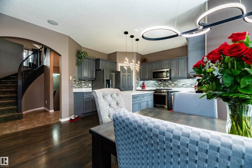 Open-concept kitchen featuring gray cabinetry, stainless steel appliances, and a mosaic tile backsplash - 704 Wildwood Point(E), Edmonton, AB 