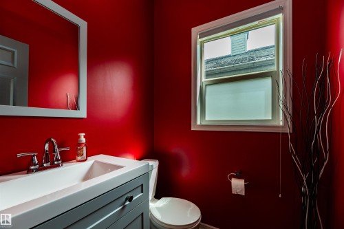 Bathroom featuring a single window, a light gray vanity with an integrated sink, chrome faucet, and a toilet - 704 Wildwood Point(E), Edmonton, AB 