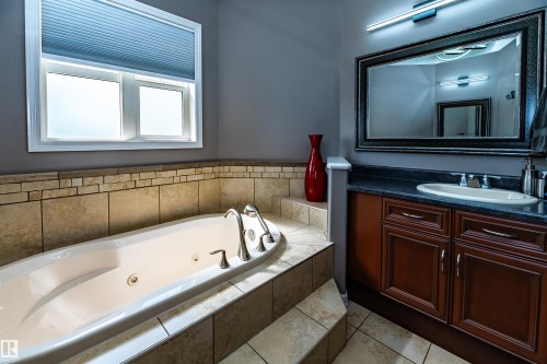 Soaking tub with brushed nickel fixtures, surrounded by neutral-toned tile - 704 Wildwood Point(E), Edmonton, AB 