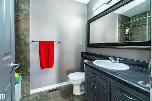 Bathroom featuring a dark grey vanity with silver hardware, an oval undermount sink, and a dark stone-finish countertop - 704 Wildwood Point(E), Edmonton, AB 