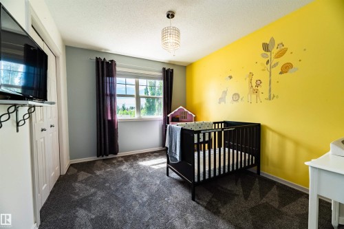 Carpeted room featuring a large window, a ceiling-mounted light fixture, and a built-in closet with bifold doors - 704 Wildwood Point(E), Edmonton, AB 