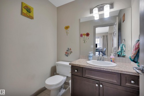Bathroom featuring a dark wood-finish vanity with a laminate countertop, an oval undermount sink, and a large wall-mounted mirror - 29 1150 Windermere Way, Edmonton, AB 
