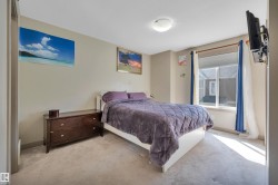 Carpeted bedroom featuring a large window with white trim, a flush-mount ceiling light fixture, neutral wall paint, and a built-in television mount - 