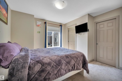 Carpeted room featuring a ceiling-mounted light fixture, six-panel interior doors, and a window with blinds - 29 1150 Windermere Way, Edmonton, AB 