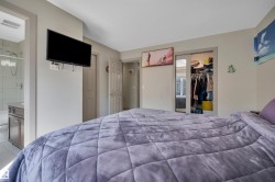 Bedroom featuring a wall-mounted television, a sliding mirrored closet door, and an entryway to a full bathroom with a walk-in shower and single vanity - 