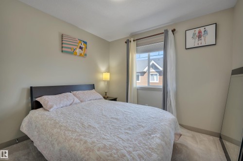 Carpeted bedroom featuring neutral wall tones and a window with blinds - 29 1150 Windermere Way, Edmonton, AB 