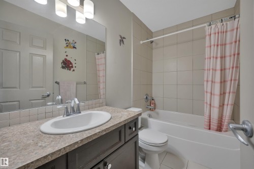 Full bathroom featuring a dark wood-finish vanity with a laminate countertop, an undermount sink, and a chrome faucet - 29 1150 Windermere Way, Edmonton, AB 