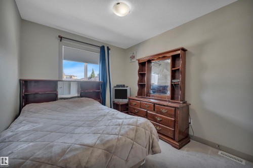 Carpeted room featuring a single window with blinds and blue drapes, light neutral wall paint, and a ceiling-mounted light fixture - 29 1150 Windermere Way, Edmonton, AB 