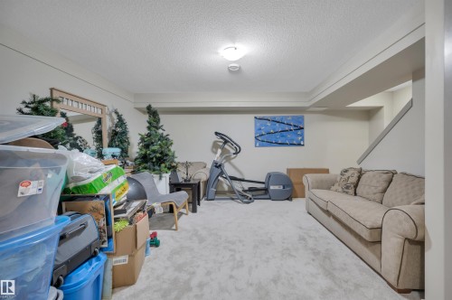 Spacious room featuring light-toned walls, textured ceiling, recessed lighting, and soft grey carpeting throughout - 29 1150 Windermere Way, Edmonton, AB 
