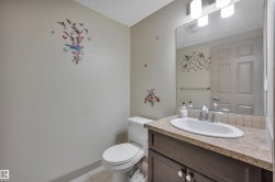 Powder room featuring a white toilet, dark wood-finish vanity with a built-in sink, and a speckled countertop - 