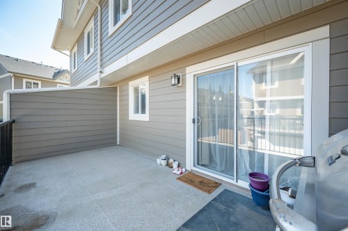 Concrete patio space featuring a privacy wall, exterior lighting, and sliding glass doors - 29 1150 Windermere Way, Edmonton, AB 
