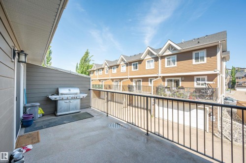 Outdoor patio featuring a concrete surface, black metal railing, and exterior wall light fixture - 29 1150 Windermere Way, Edmonton, AB 