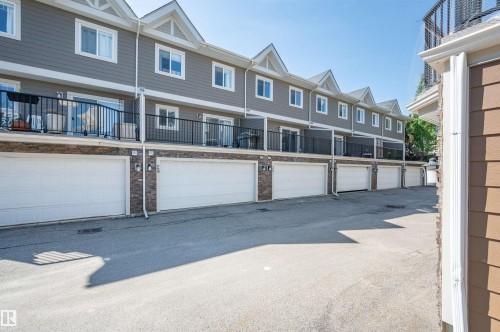 Multi-story townhouse facade featuring gray horizontal siding and a stone veneer base - 29 1150 Windermere Way, Edmonton, AB 