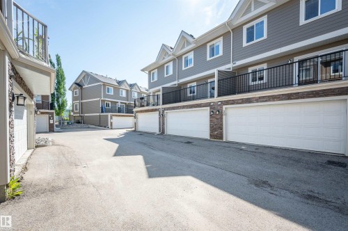 Townhome exteriors featuring horizontal siding, white trim, and stone accents - 29 1150 Windermere Way, Edmonton, AB 