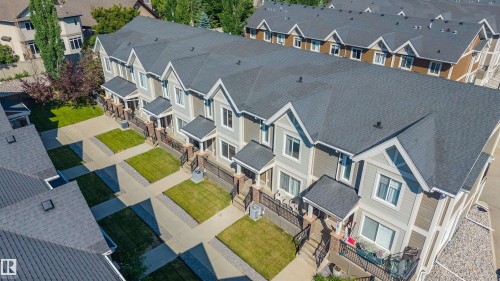 Contemporary townhome exteriors featuring gabled roofs with dark shingles, light gray siding, and contrasting brown accents - 29 1150 Windermere Way, Edmonton, AB 
