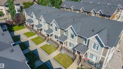 Contemporary townhome exteriors featuring gabled roofs with dark shingles, light gray siding, and contrasting brown accents - 