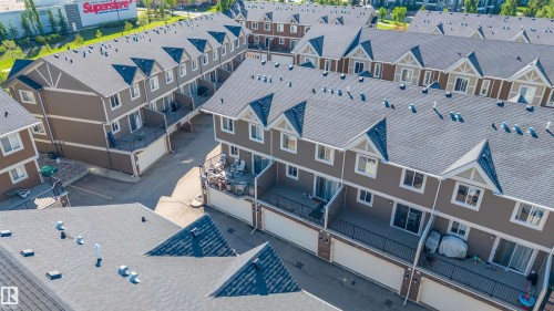 Residential townhome development featuring multiple units with dark shingle roofs, dormer windows, and light tan siding - 29 1150 Windermere Way, Edmonton, AB 