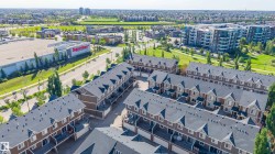 Aerial perspective showcasing multiple rows of multi-story townhomes with dormer windows and rear-facing balconies - 