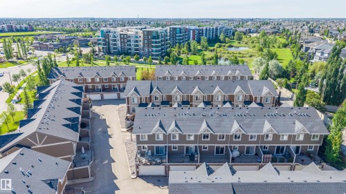 Aerial perspective highlighting a townhome community with pitched dark gray roofs and light brown siding - 29 1150 Windermere Way, Edmonton, AB 