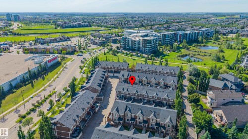 Aerial perspective showcasing a community of townhome-style residences with dark roofs and light-colored siding - 29 1150 Windermere Way, Edmonton, AB 