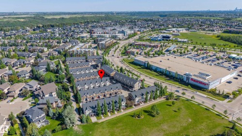 Aerial perspective showcasing a residential area featuring multiple rows of multi-story townhomes, surrounded by established green spaces and mature trees - 29 1150 Windermere Way, Edmonton, AB 