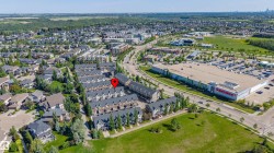 Aerial perspective showcasing a residential area featuring multiple rows of multi-story townhomes, surrounded by established green spaces and mature trees - 
