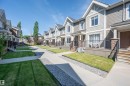 Multi-level townhome featuring a stone-clad entry, covered porch, and a private front yard with manicured lawn - 29 1150 Windermere Way, Edmonton, AB 