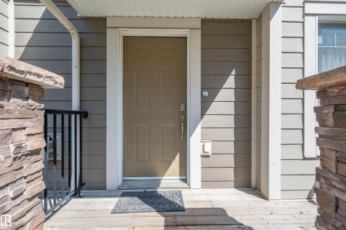 Entryway featuring a wood-finish porch, stone veneer accents, and horizontal siding - 29 1150 Windermere Way, Edmonton, AB 