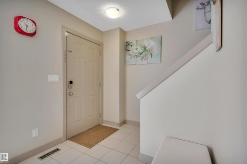 Entryway featuring a panel door, ceiling-mounted light fixture, and tile flooring - 29 1150 Windermere Way, Edmonton, AB 