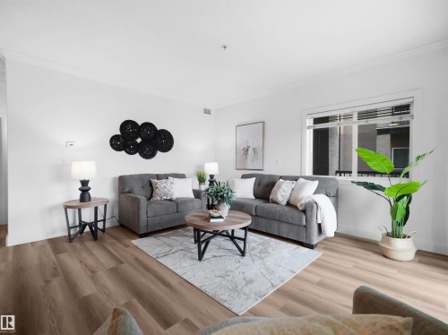 Spacious interior featuring wood-finish flooring, white walls, and a large window with horizontal blinds - 104 14612 125 Street, Edmonton, AB 