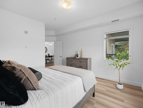 Bright room featuring light wood-finish flooring, white baseboards, and a large window with blinds - 104 14612 125 Street, Edmonton, AB 