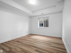 Spacious room featuring wood-finish flooring, white baseboards, and bright white walls - 
